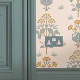 Paintable white double socket painted pastel green fixed to wall with pastel green and orange wallpaper and pastel green wooden door