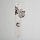 Poplar Long Plate Sprung Door Knob & Thumbturn in Polished Nickel, mounted on a white wall.