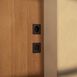 Wooden door with two black Regent Thumbturn handles against a light-colored wall.