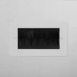 Double Module Brush Plate in Paintable Black finish for 2G Sockets & Modules, mounted on a textured white wall.