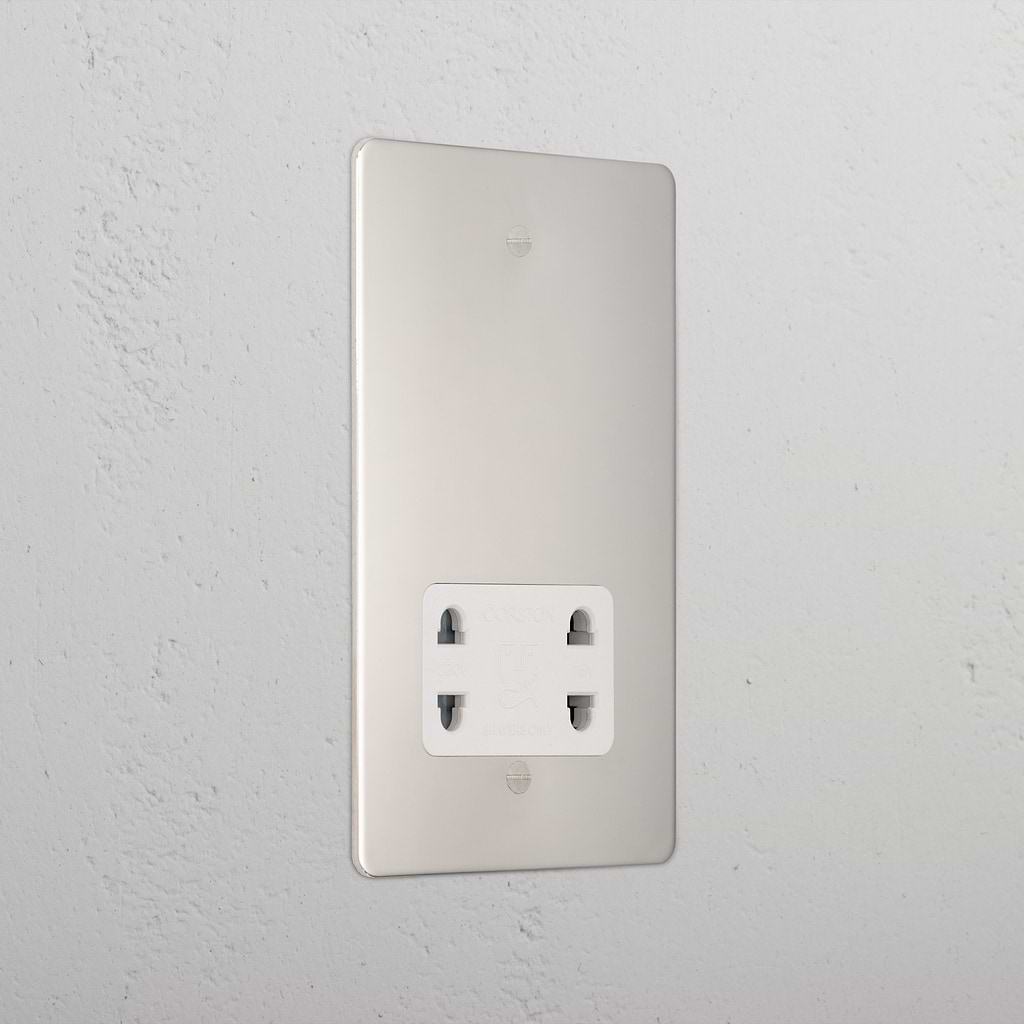 Polished nickel shaver socket with white insert on grey wall. 