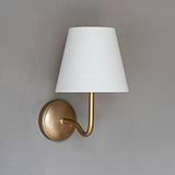Malvern Medium Wall Light in Alabaster White with antique brass finish, mounted on gray wall.