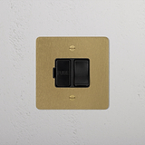 Antique Brass Black Switched Fused Spur (FCU) - Isolator Switch on a textured white wall.