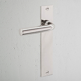 Apsley Long Plate Sprung Door Handle in polished nickel with rectangular backplate on a white textured wall.