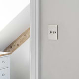2G Two Way Toggle Slimline Switch in polished nickel on a white wall with wood beam and cabinet background.