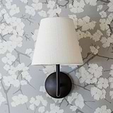 Malvern Medium Wall Light in Alabaster White with beige shade and bronze accents against floral wallpaper.