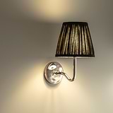 Medium Malvern Wall light in Deep Green at an angle affixed to a wall and turned on