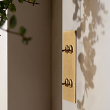 4G Vertical Two Way Toggle Switch in antique brass finish, mounted on a wall with plant shadows.