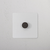 Paintable bronze 1G two-way dimmer switch with a black knob on a square panel, installed on a white wall.