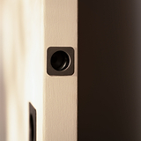 Close-up of a door with a bronze lock plate and elegant Regent Recessed Edge Pull in soft light.
