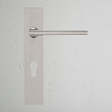 Clayton Long Plate Sprung Door Handle & Euro Lock in polished nickel on a textured white wall.