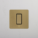 1G Centre Retractive Rocker Switch in Antique Brass Black on a white wall, part of 1G Switches & Dimmers.