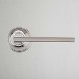 Clayton Unsprung Door Handle - Polished Nickel on textured white wall.