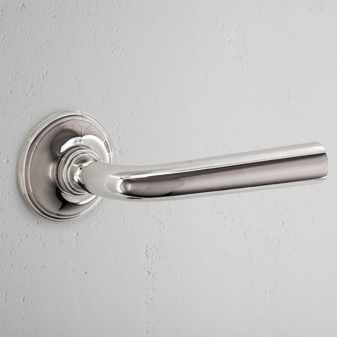 Apsley Fixed Door Handle in polished nickel on a light gray wall.