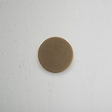 Onslow Unsprung Door Knob in Antique Brass finish mounted on a textured white wall.
