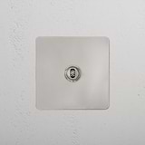Polished nickel 1G centre retractive toggle switch on a textured white wall, from 1G Switches & Dimmers line.