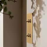 4G Vertical Two Way Toggle Switch in antique brass finish, mounted on a wall with plant shadows.