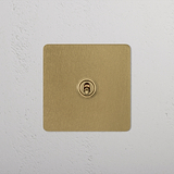 Antique brass 1G double pole toggle switch on white textured wall, ideal for switches & dimmers.