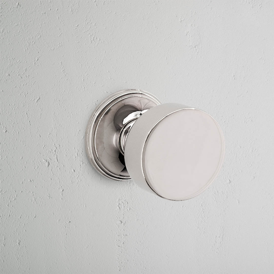 Close-up of the Onslow Sprung Door Knob in polished nickel on a textured white wall.