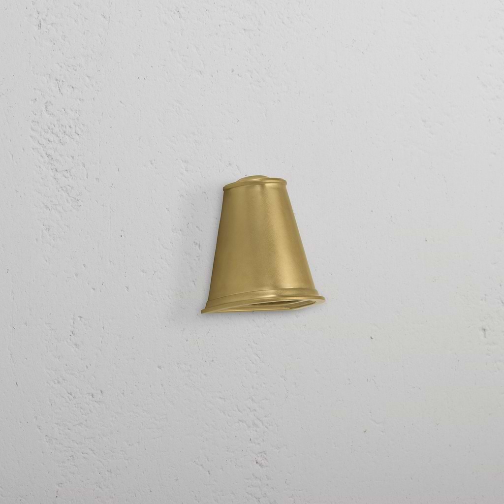 Southwark Mast Light – Antique Brass small wall light with a cone-shaped shade mounted on a white textured wall.