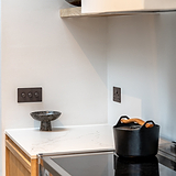 Bronze 3G Two Way Dimmer Switch for modern interiors, shown alongside a black pot and marble bowl on a counter.
