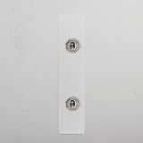 Close-up of a paintable polished nickel 2G architrave two-way toggle switch with two metal screws on a white surface.