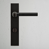 Bronze Harper Long Plate Sprung Door Handle & Thumbturn on a textured white wall.