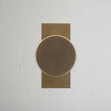 Onslow Short Plate Fixed Door Knob in Antique Brass on a textured white door, showcasing classic elegance.