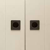 Close-up of minimalist white sliding doors with bronze Regent Recessed Small Pull handles.