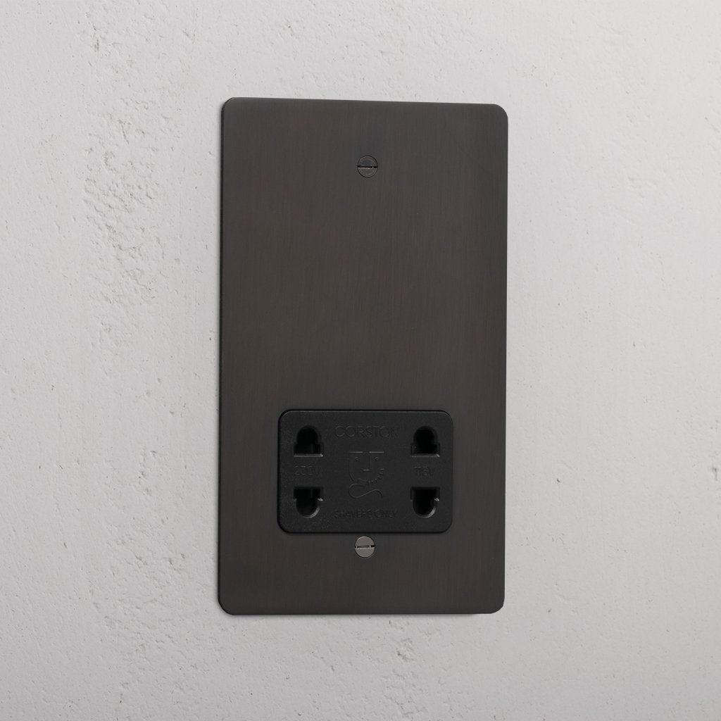 Bronze shaver socket with black insert on grey wall. 
