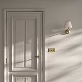 Malvern Medium Wall Light in pleated alabaster white with antique brass sconce, mounted on a sunlit white wall.