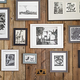 Antique brass and black double socket fixed to wooden slatted wall with various sized framed pictures