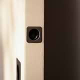 Close-up of a door with a bronze lock plate and elegant Regent Recessed Edge Pull in soft light.