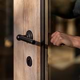 Canning Key Escutcheon in bronze on a wooden door with glass panel and black handle, for hardware accessory use.