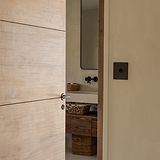 Bronze Clayton Flush Rose Sprung Door Handle on a partially open wooden bathroom door.