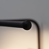 Close-up of the minimalist black rod end, akin to Harrow Picture Light 400mm, on a blurred neutral backdrop.