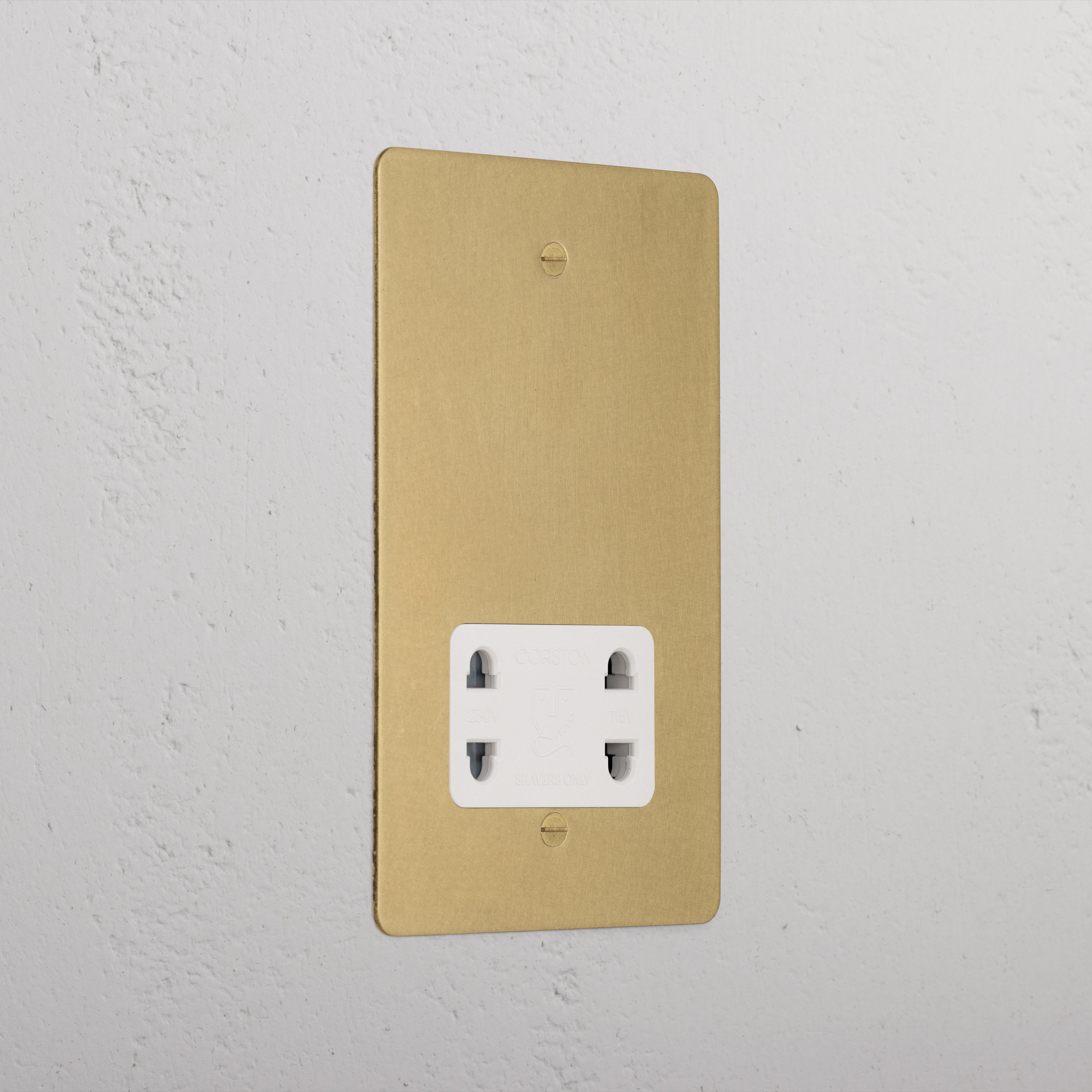 Antique brass shaver socket with white insert on grey wall. 