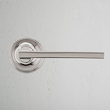 Clayton Unsprung Door Handle - Polished Nickel on textured white wall.