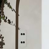 4G Vertical Two Way Toggle Switch in Paintable Bronze on a wall with leafy shadows, compatible with 4G Switches & Dimmers.