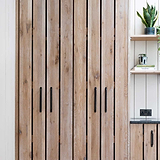 Bronze Kilburn Furniture Handle 224mm on wooden cabinet; nearby shelves with plants and sleek black power outlet visible.
