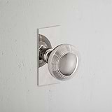 Polished Nickel Poplar Short Plate Fixed Door Knob on white background. Elegant and contemporary design.