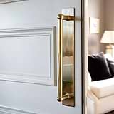 Antique brass Harper Single Pull Handle with Plate 500mm on a partially open white door.