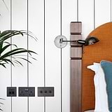 Bronze 3G Intermediate Toggle Switch on paneled wall next to bed, featuring plants and bronze accents.