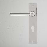 Harper Long Plate Sprung Door Handle & Euro Lock in polished nickel on a textured white wall.