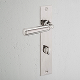 Digby Long Plate Sprung Door Handle & Thumbturn in polished nickel on a rectangular backplate against a white wall.
