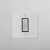 1G Retractive Rocker Switch, Paintable Polished Nickel Black finish, mounted on a textured wall.