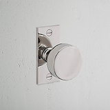 Onslow Short Plate Fixed Door Knob in polished nickel on a square backplate, contrasting with a light wall.