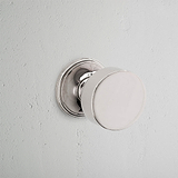 Close-up of Onslow Fixed Door Knob - Polished Nickel on a textured white wall.