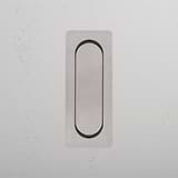 A polished nickel vertical metal switch on a white textured wall.