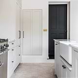 Antique Brass 4G two way dimmer switch fixed to white kitchen wall next to black door